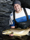 An employee standing in the water holding a brood stock fish