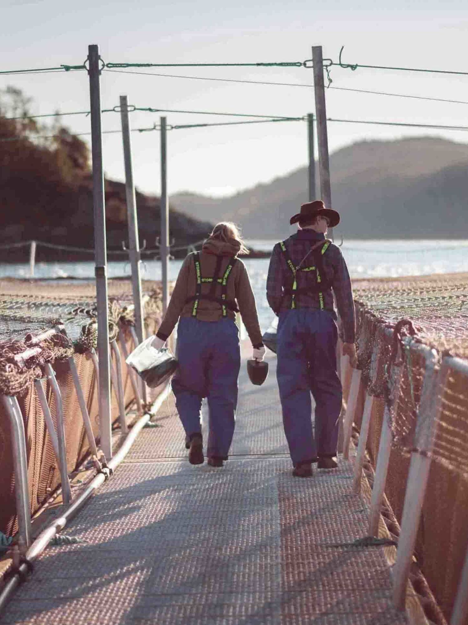 Two employees walking down the gangaway between pens at a seasite